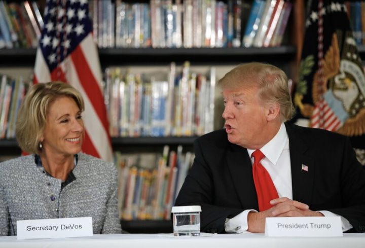 Education Secretary Betsy DeVos listens at left as President Donald Trump speaks during a round table discussion at Saint Andrew Catholic School on March 3, 2017, in Orlando, Fla.